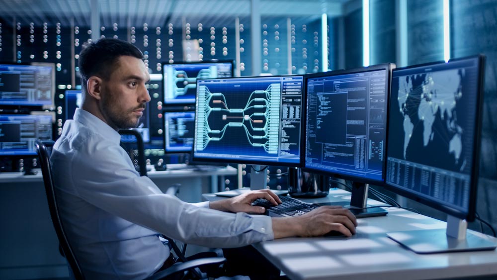 Man sitting at desk analyzing cyberthreats